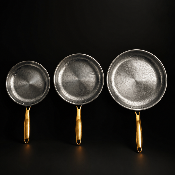 Top-down view of the three pans side by side, from smallest to largest, showing the patterned interiors and gold-toned handles.