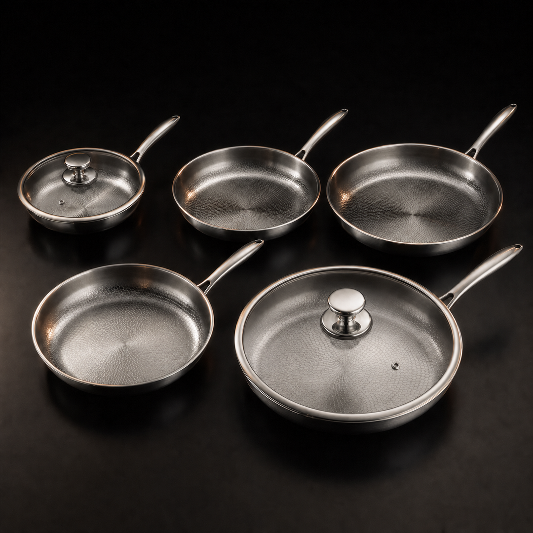 Five silver hammered metal frying pans of different sizes with two glass lids.