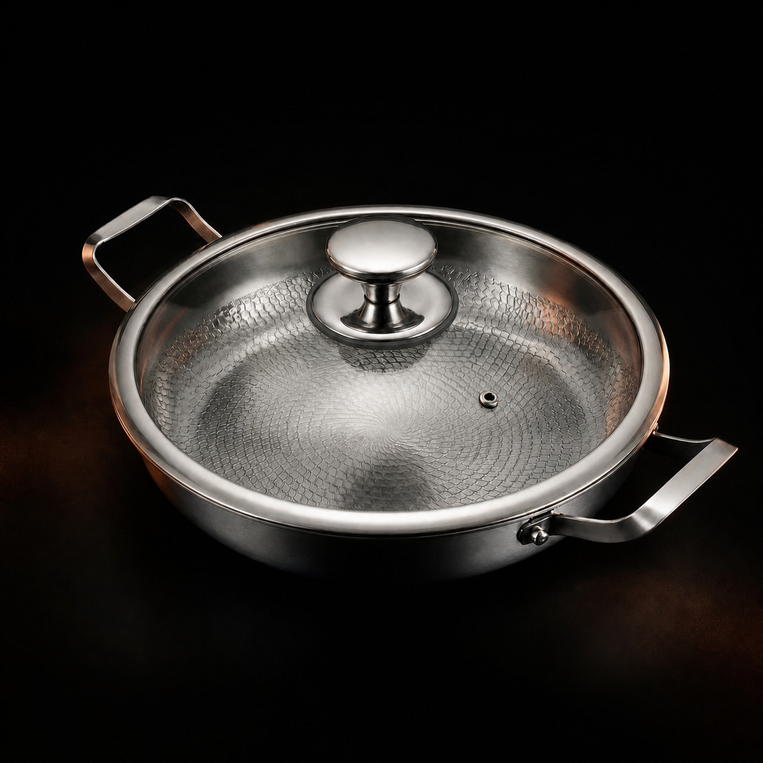 Pan with a clear glass lid and a polished metal knob on a black background, the hammered interior visible through the glass. 3
