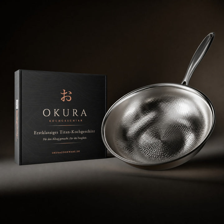 Wok pan tilted next to its black gift box, showing the hammered interior and long handle against a dark backdrop. 8
