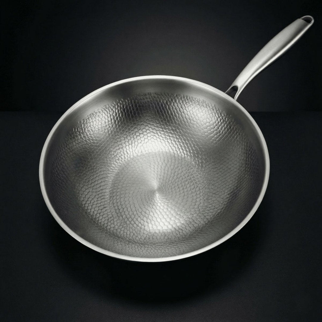 Hammered titanium wok pan top view with a long steel handle.