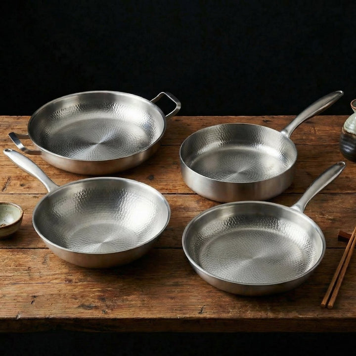 Four hammered pans on a rustic wooden table beside chopsticks.