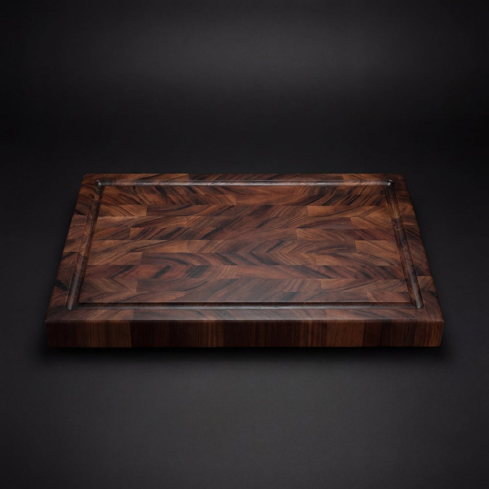 Straight-on view of the walnut board's end-grain surface, showing swirling grain patterns and the juice groove running around the edge. 2