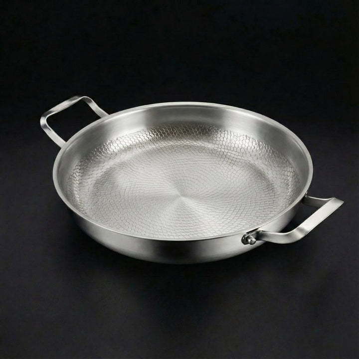 Detail of the wide two-handled pan with a hammered interior pattern radiating outward.