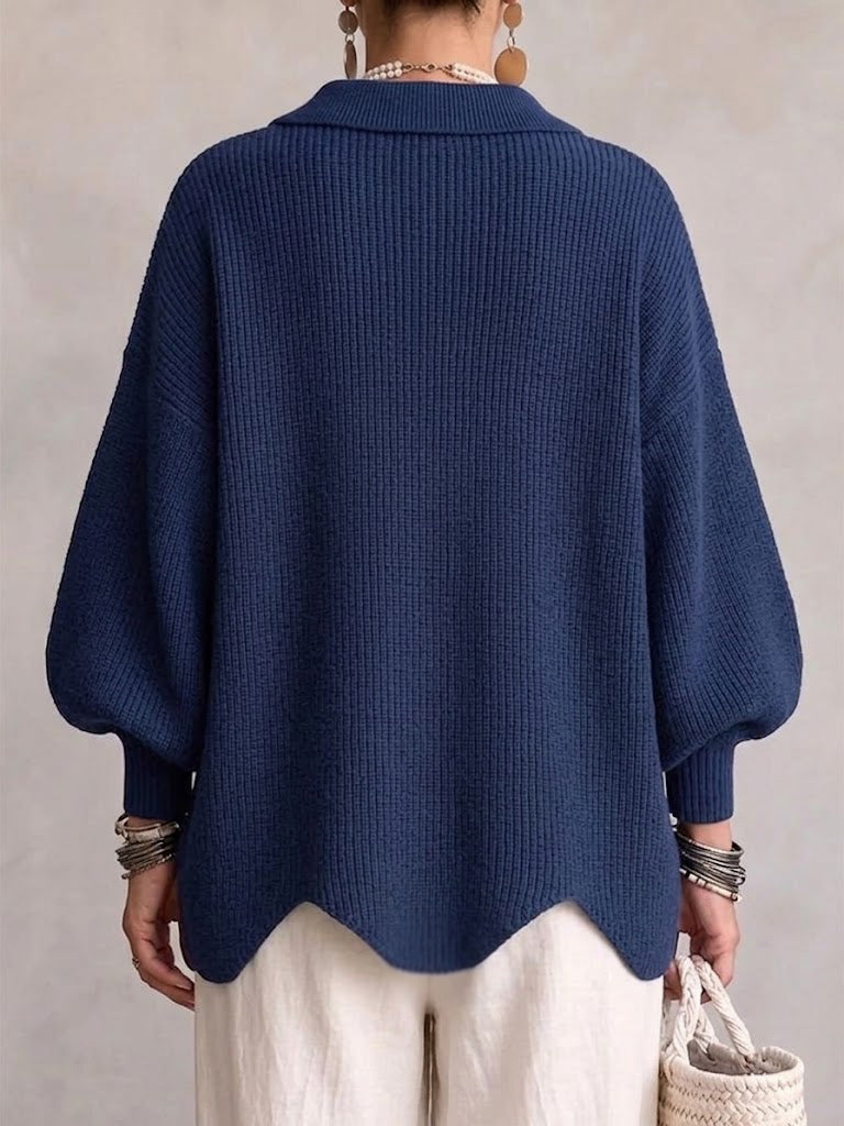 Navy ribbed cardigan, back view, with a folded collar, balloon sleeves and a scalloped hem.