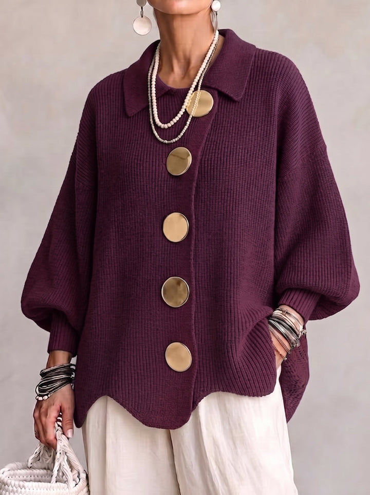 Front view of the deep plum ribbed cardigan on a model, showing five round gold buttons, pointed collar and wavy hem. 2