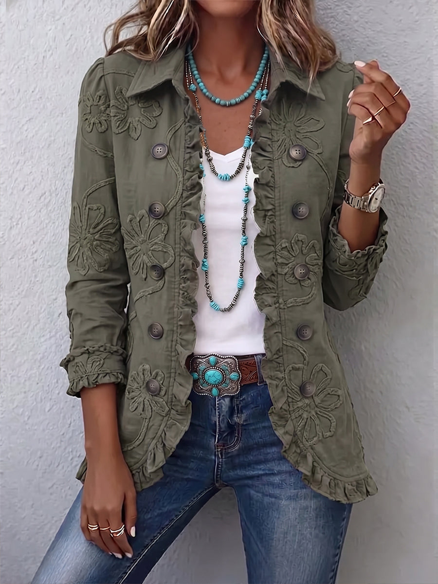 Front view of an olive green jacket with embossed flowers, ruffled edges and buttons, worn open over a white top and jeans. 1