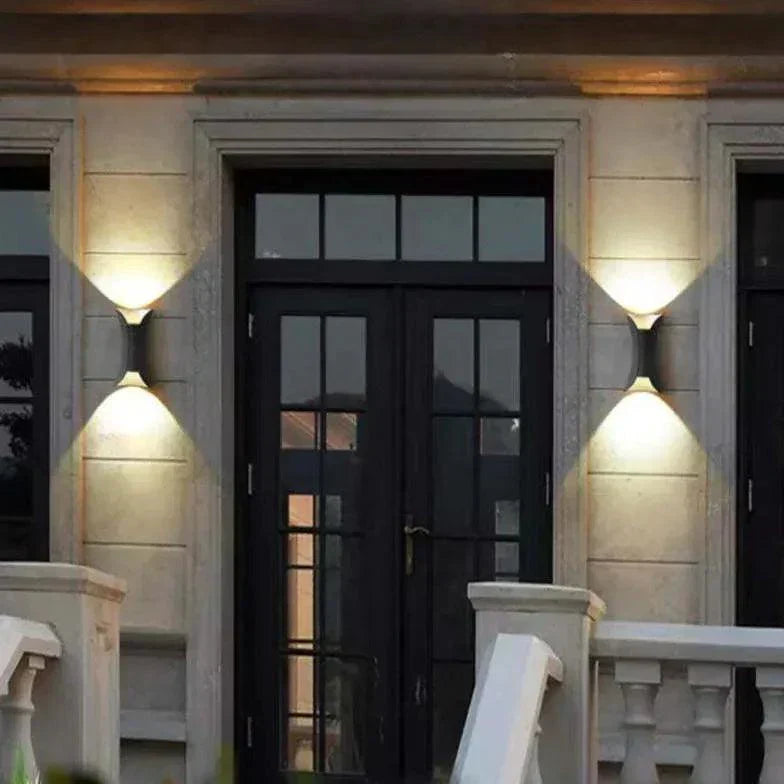 Black LED outdoor wall light with gold accents mounted on a stone facade.