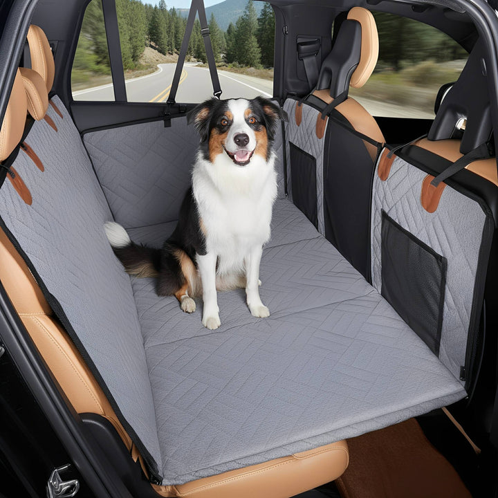 Gray dog back seat extender with a black, white and tan dog sitting upright in a car