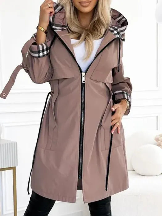 Woman wearing the mocha-brown hooded zip-up jacket open over a white top, with plaid lining visible at the hood and cuffs.