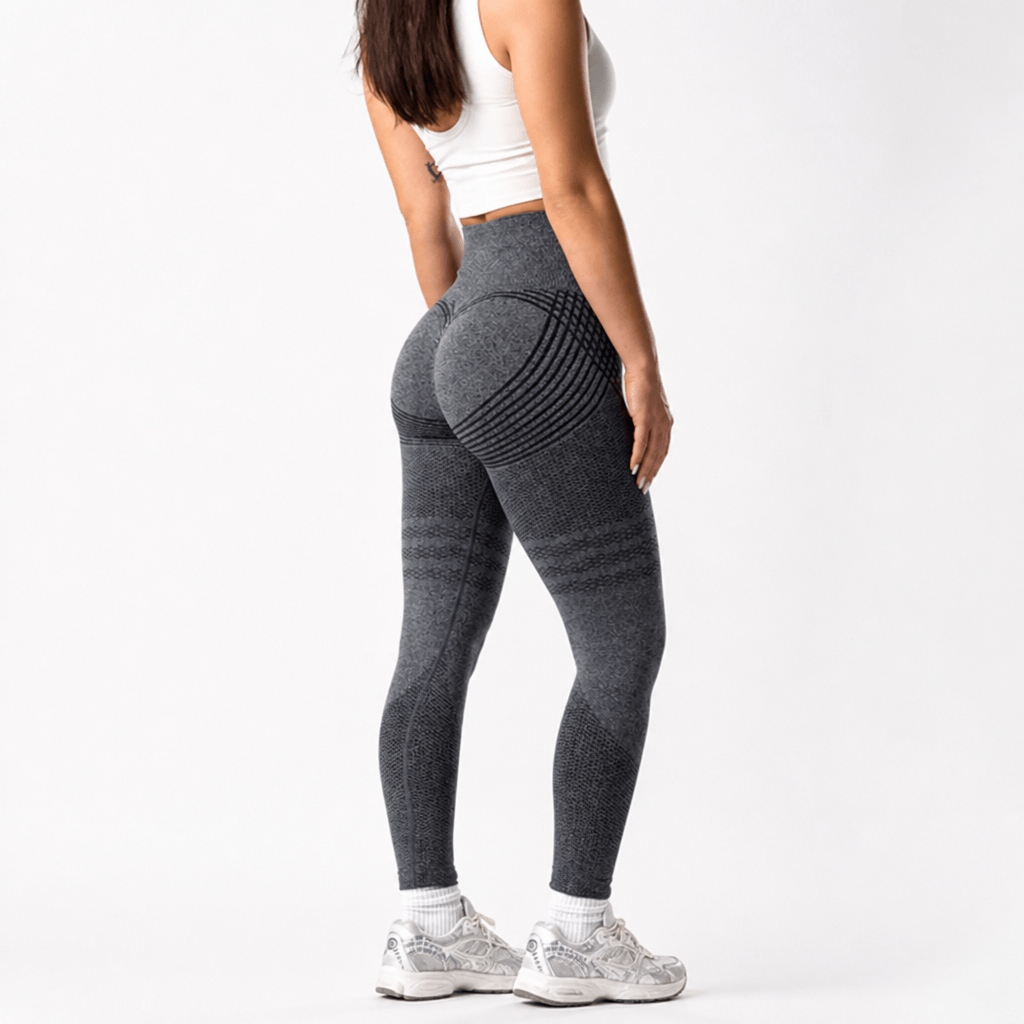 Back view of charcoal gray seamless leggings with curved black stripes over the hips, worn with a white crop top and sneakers. 23