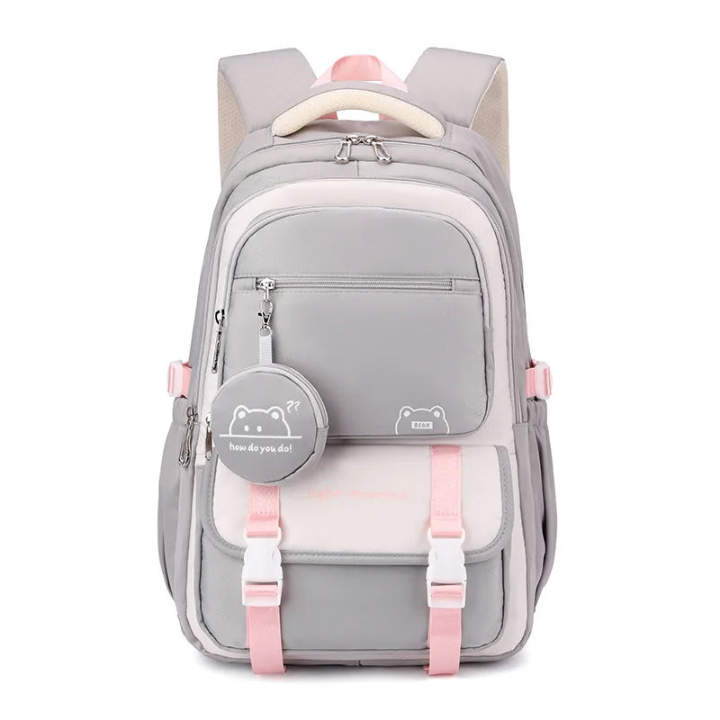 Front view of the same backpack in gray and cream with pink strap accents, white buckles and a gray bear charm pouch. 10