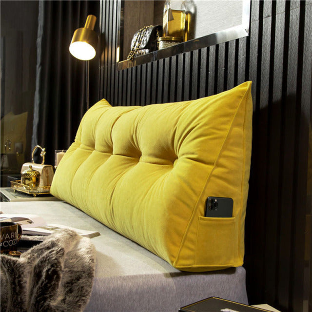 another view of a yellow tufted velvet wedge pillow with a phone in the side pocket.