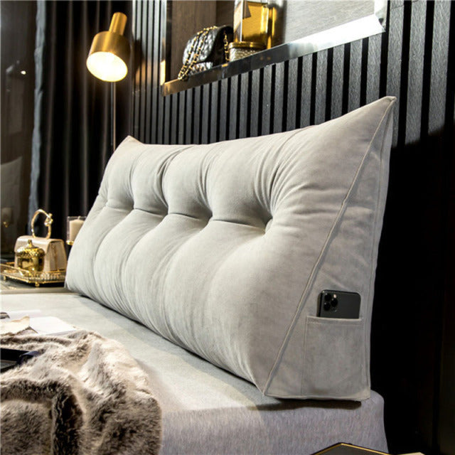 another view of a pale gray tufted velvet wedge pillow with a phone in the side pocket.