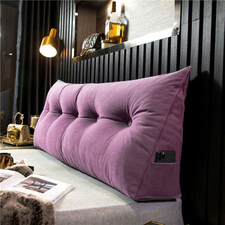 another view of a purple tufted velvet wedge pillow with an open book nearby.