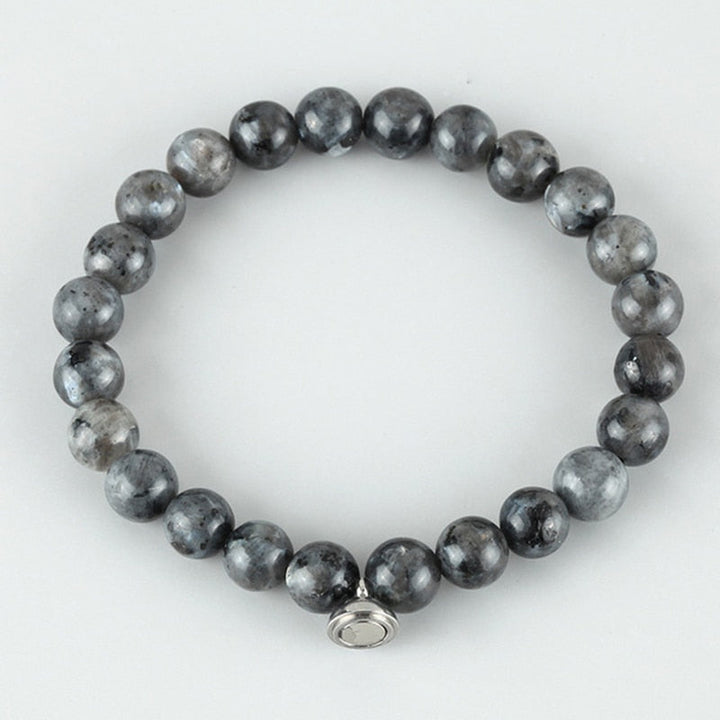 Flat lay of a bracelet of round gray beads with dark speckled patterns and a silver magnetic clasp 4