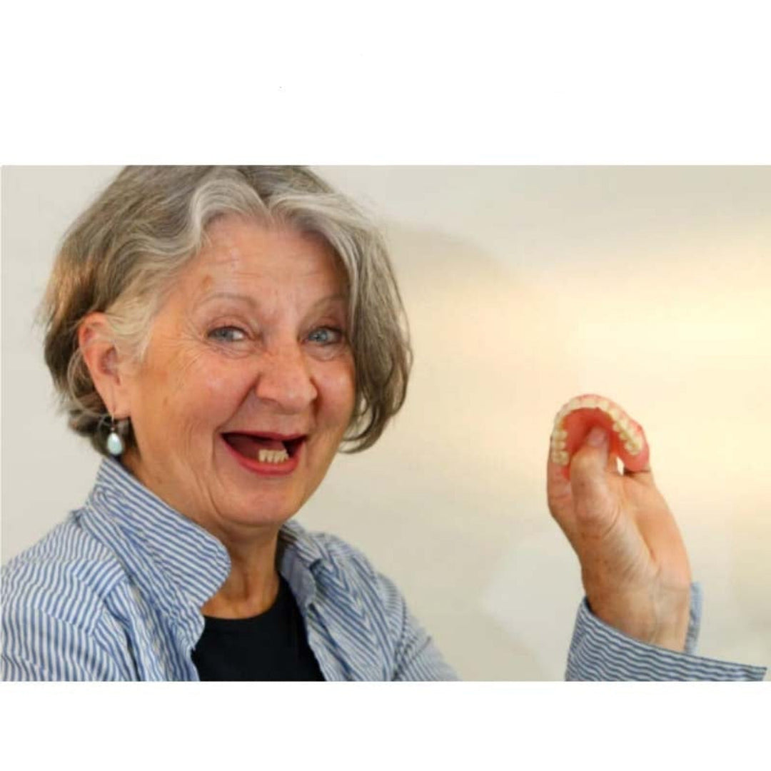 Smiling gray-haired woman holding a flexible upper denture detail