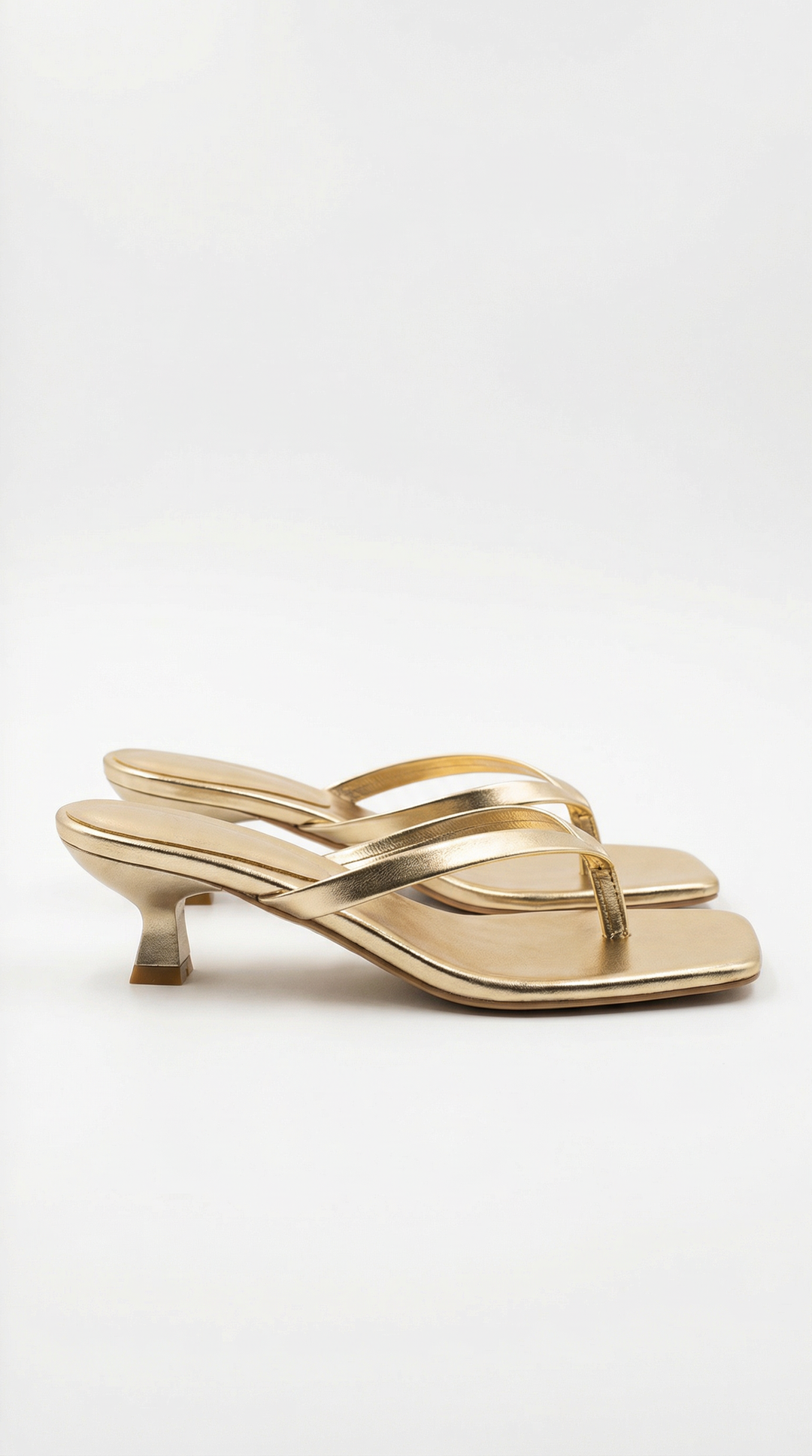Pair of metallic gold square-toe thong sandals with a slim flared kitten heel