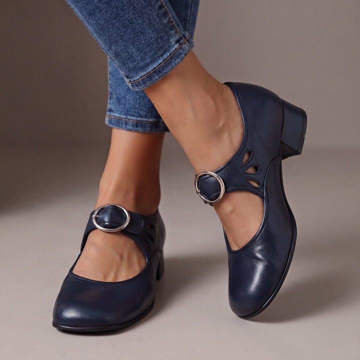 Blue leather block-heel pumps with a round silver buckle strap and teardrop cutouts, another view.