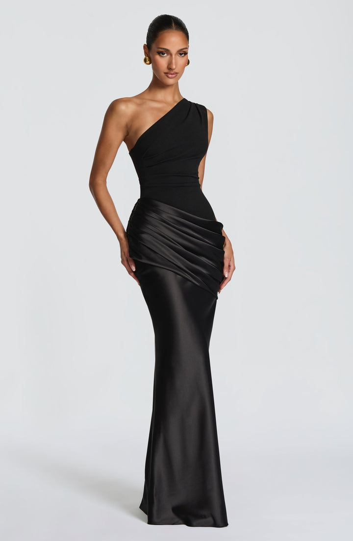 Model wearing the black one-shoulder maxi dress, full-length front view, with a pleated crepe bodice and draped satin hip panel. 41