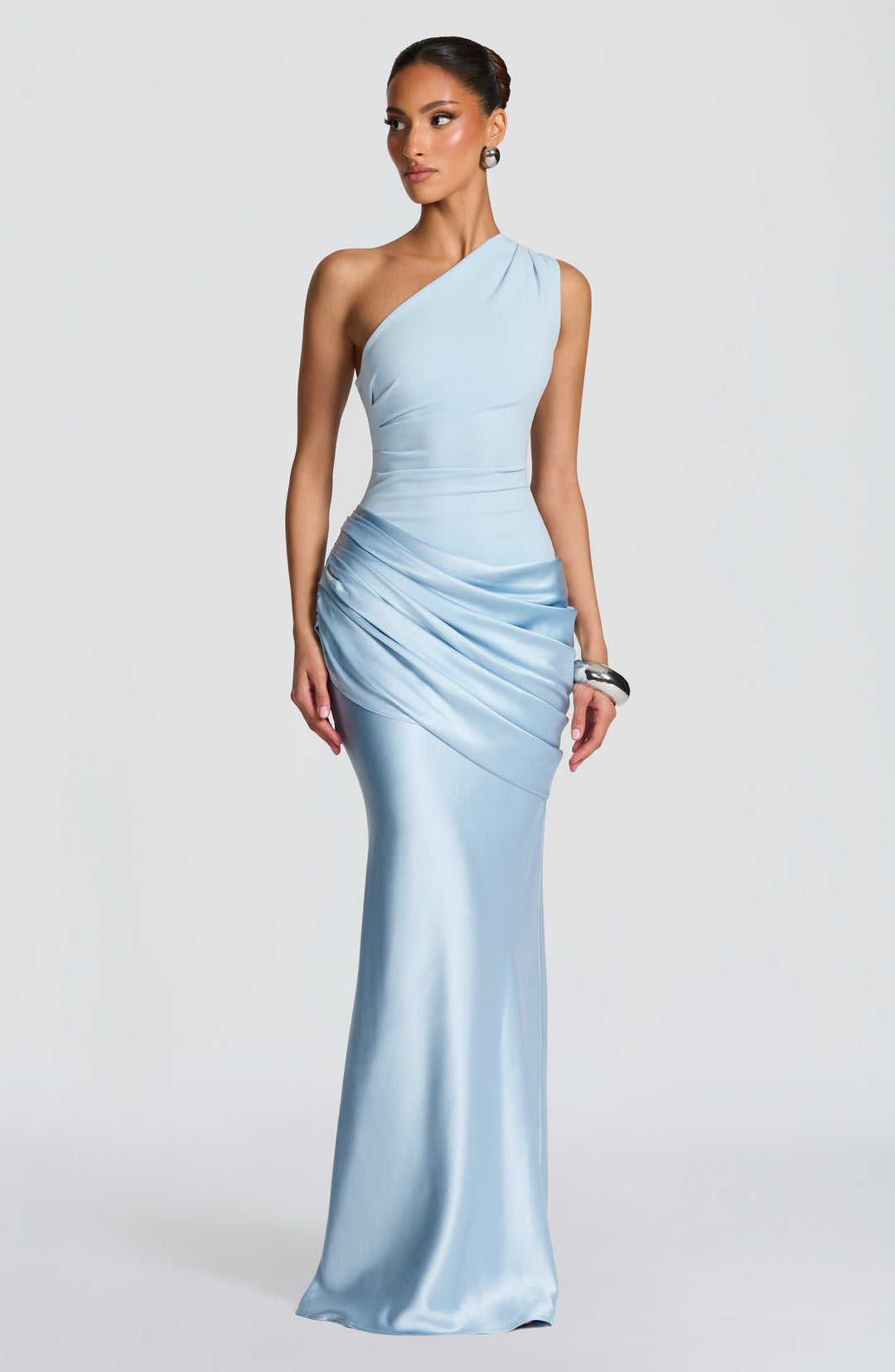 Model wearing the dress in pale powder blue, with silver earrings and a chunky silver cuff, glancing to the side. 24