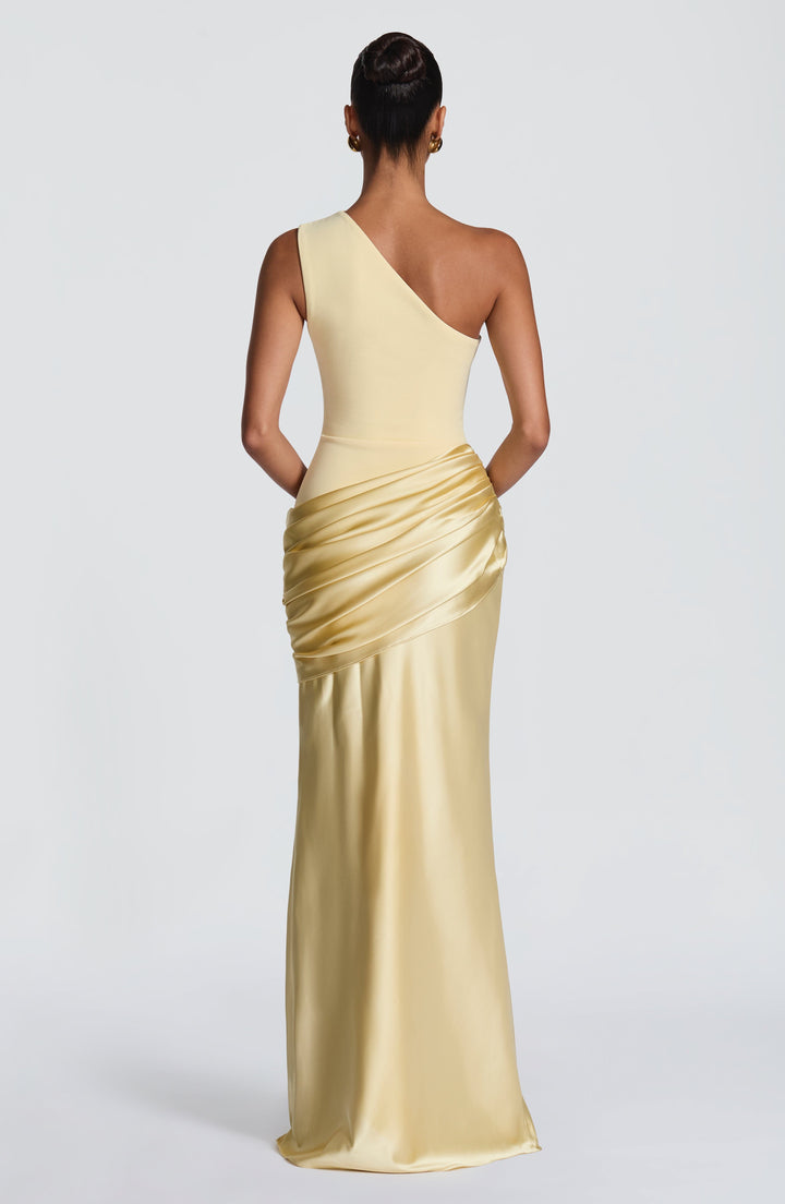 Back view of the pale yellow one-shoulder maxi dress, showing the diagonal shoulder line and ruched satin hip drape. 46