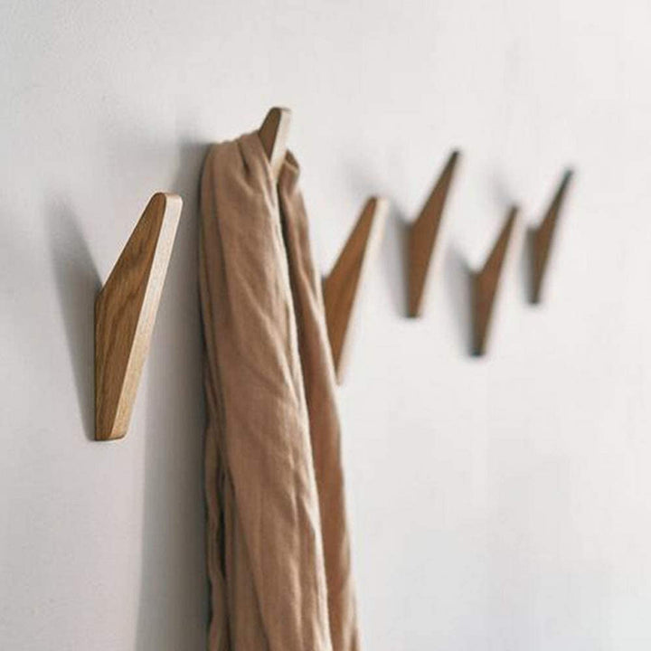 Row of angled light wooden hooks mounted on a white wall, with a tan scarf draped over one hook. 2