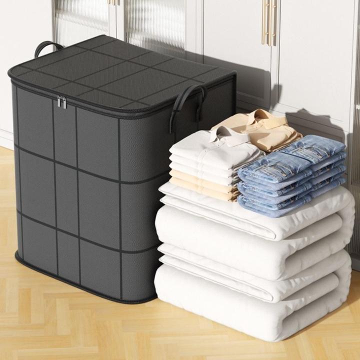 Grey storage bag beside folded bedding and clothing.