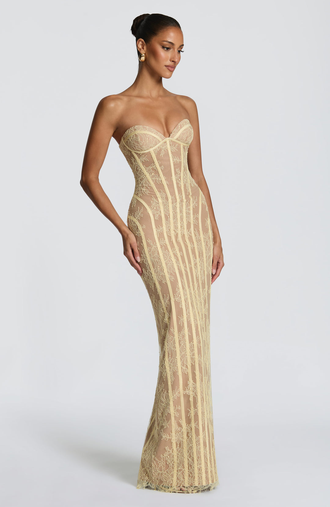 Three-quarter view of the soft yellow strapless lace gown, showing the curved seams and fitted floor-length silhouette.