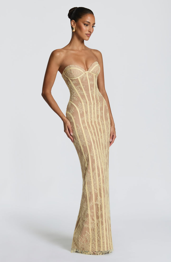 Three-quarter view of the soft yellow strapless lace gown, showing the curved seams and fitted floor-length silhouette.