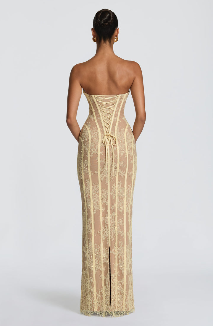 Back view of the soft yellow lace dress showing the lace-up corset back, tied ribbon ends and a center back slit.