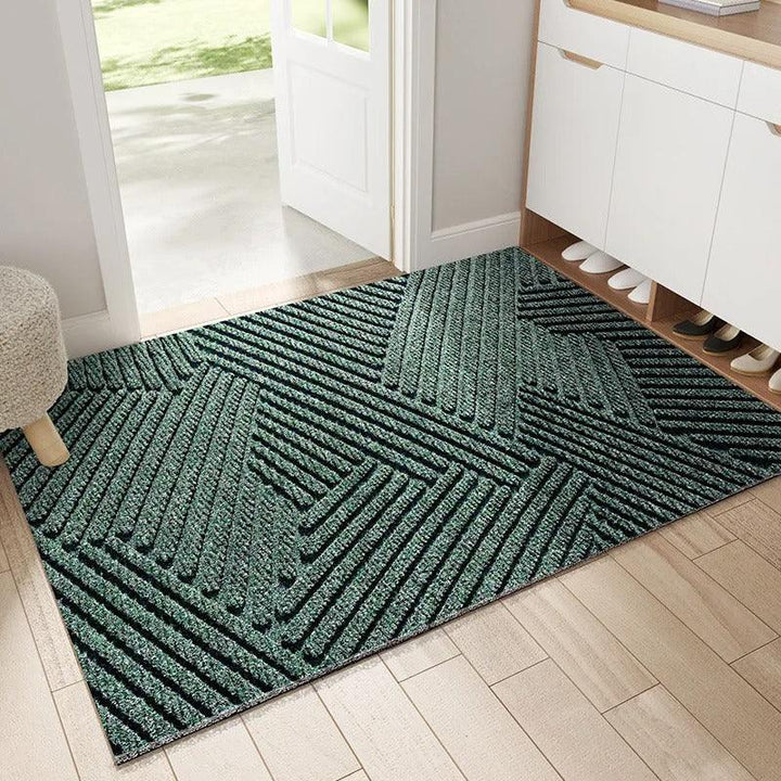 Green geometric plastic doormat by an entryway with a shoe cabinet and wood floor.