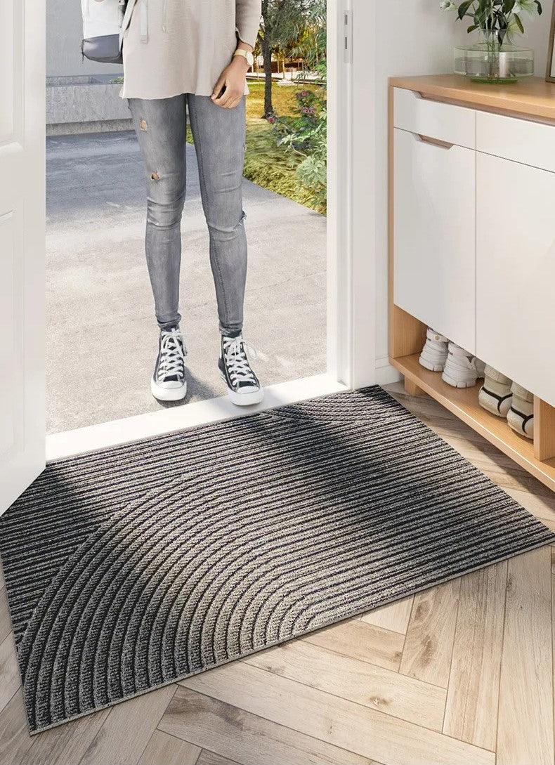 Gray ridged doormat at an open door with a person standing nearby.