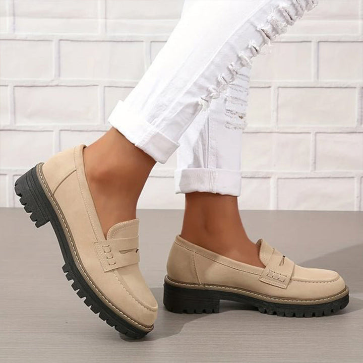 Beige loafers with black soles worn with cuffed white jeans.