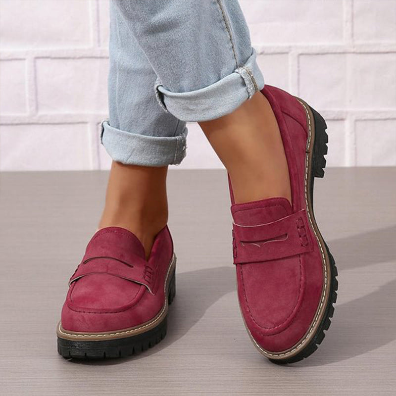 Burgundy loafers with cream contrast stitching and black soles worn with rolled jeans.