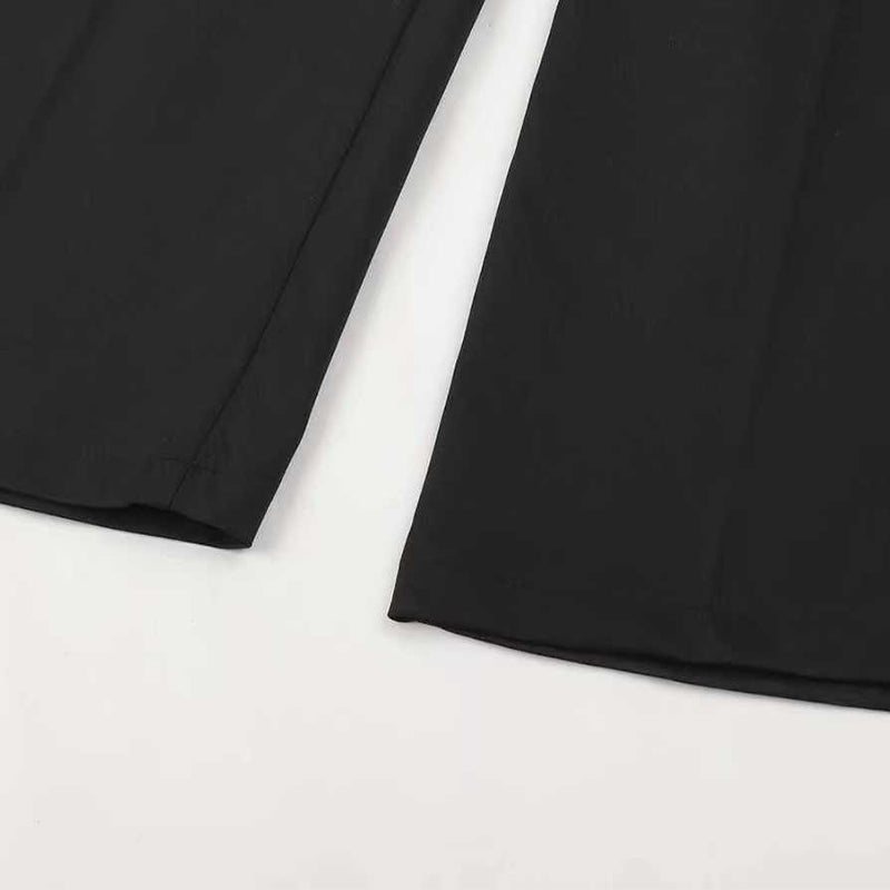 Close-up of black pant hems laid flat with the stitched bottom edge and crease down each leg.