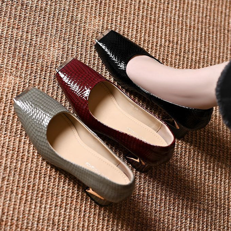 Top-down view of gray, burgundy and black snake-embossed pumps lined up on a woven mat, showing the beige insoles and metal toe caps. 6