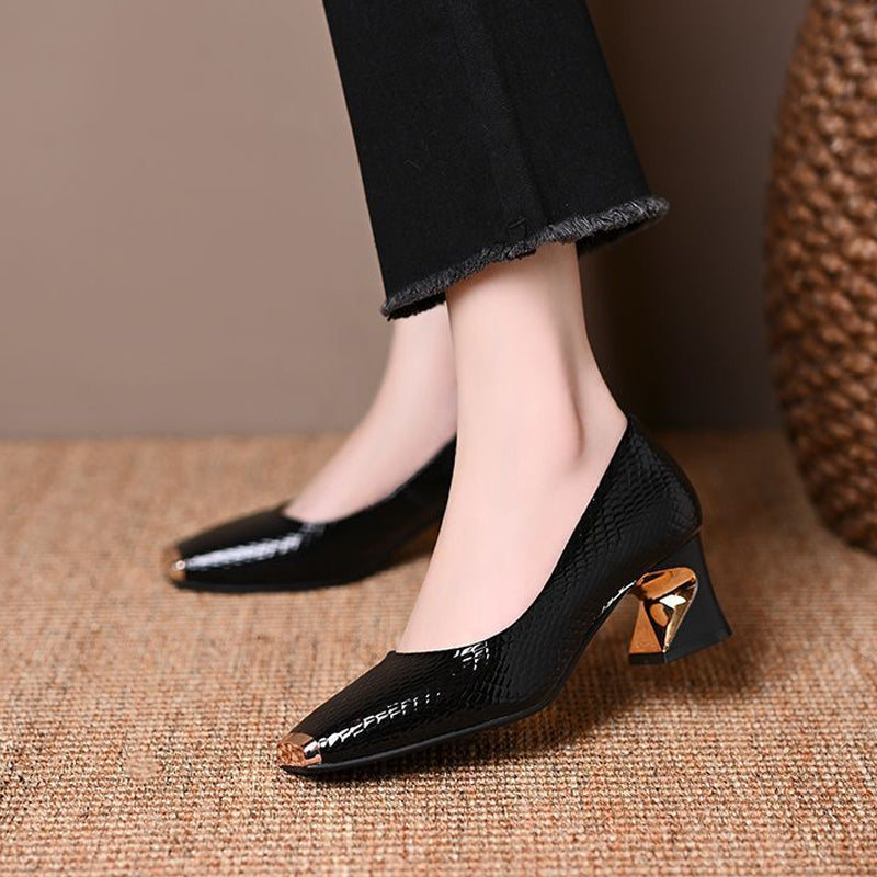 Side view of a glossy black snake-embossed pump with gold toe tip and a twisted gold-accented heel, worn with black frayed pants. 4