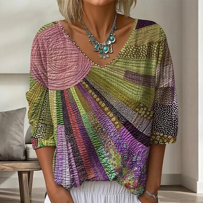 Close-up of the patchwork blouse in a muted olive green, mauve pink and purple sunburst colorway with three-quarter sleeves. 4