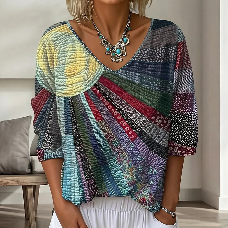 Close-up of the V-neck blouse in a darker colorway of teal, navy, burgundy and gray patchwork with a pale yellow sun motif. 5