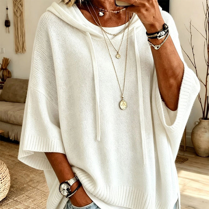 Women's white hooded knit sweater detail over a white tee with drawstrings, ribbed hem and cuffs, and layered gold necklaces.