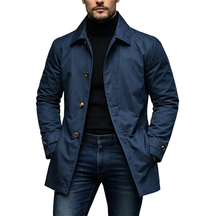 Man wearing the navy blue version of the coat with brass-toned buttons, layered over a black turtleneck and jeans. 4