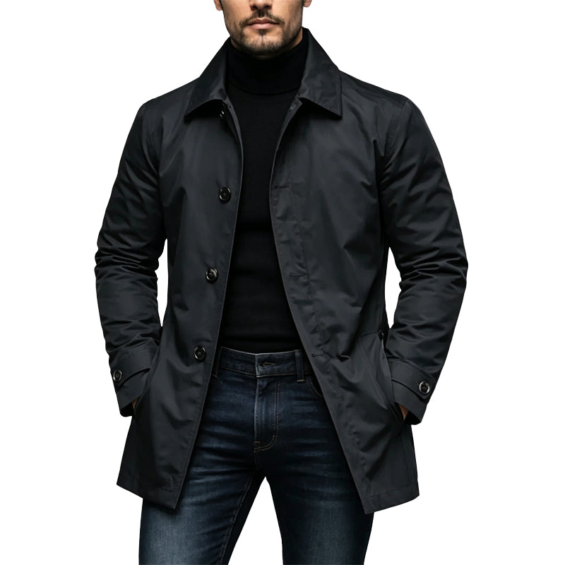 Man wearing the black button-front trench coat over a black turtleneck and dark jeans, hands in pockets. 1