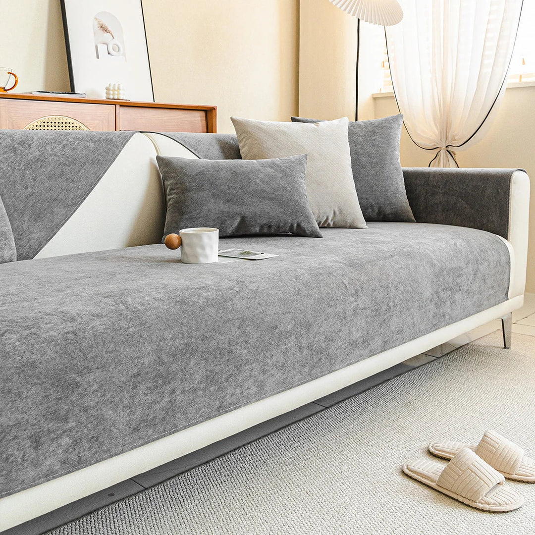 Gray chenille cover on a cream sofa in a bright living room, with a mug, cushions and slippers nearby. 10