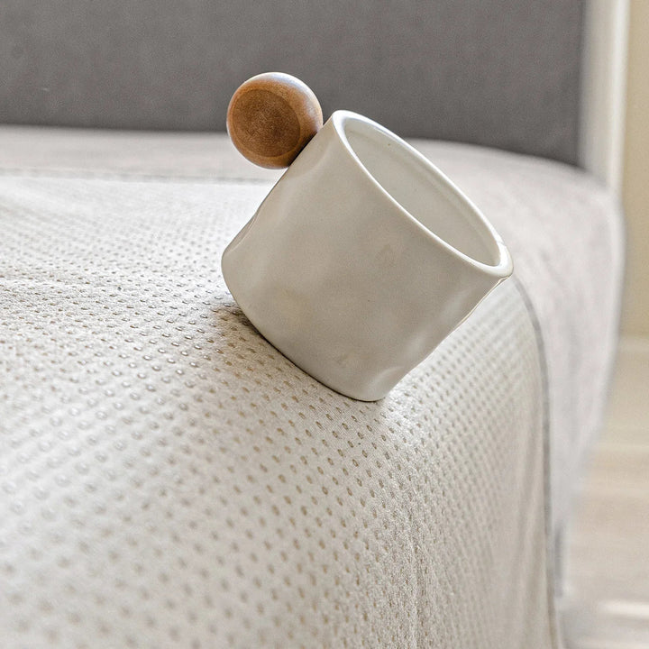 Small white mug with a wooden ball handle resting on the cover's beige dotted non-slip underside. 7