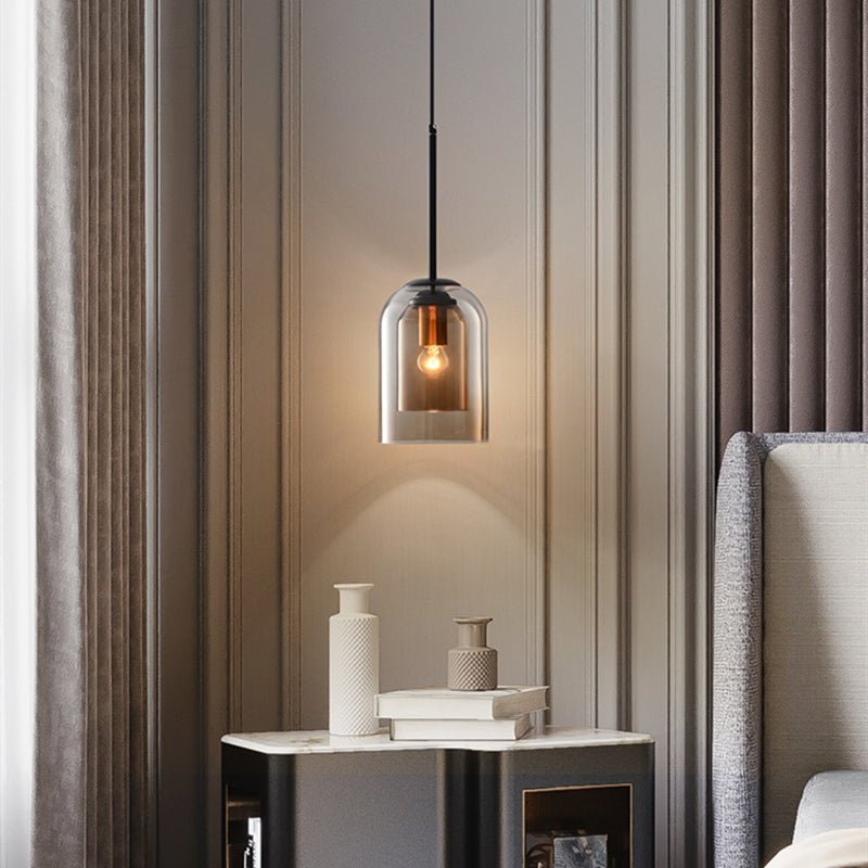 Smoke gray pendant lamp glowing above a marble nightstand beside a bed with curtains 2