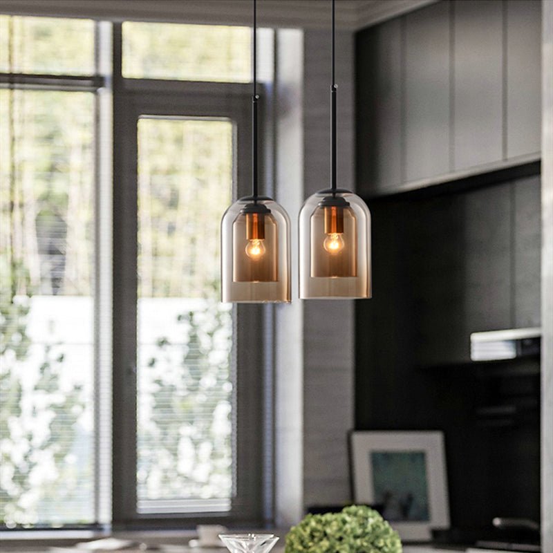 Two amber glass pendants with exposed bulbs hang by a large window in a modern kitchen 4