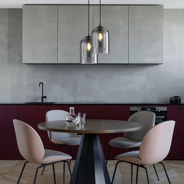Two smoke gray pendants at different heights above a round dining table and pink chairs in a kitchen 7
