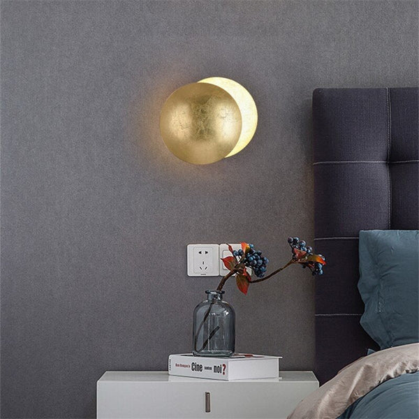 Gold disc lamp on a gray wall above a nightstand with a vase of berries 7