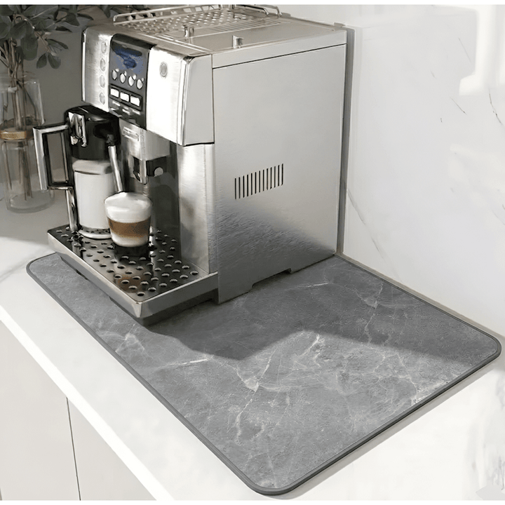Gray marble-patterned mat with a darker border beneath a silver espresso machine on a white counter 12